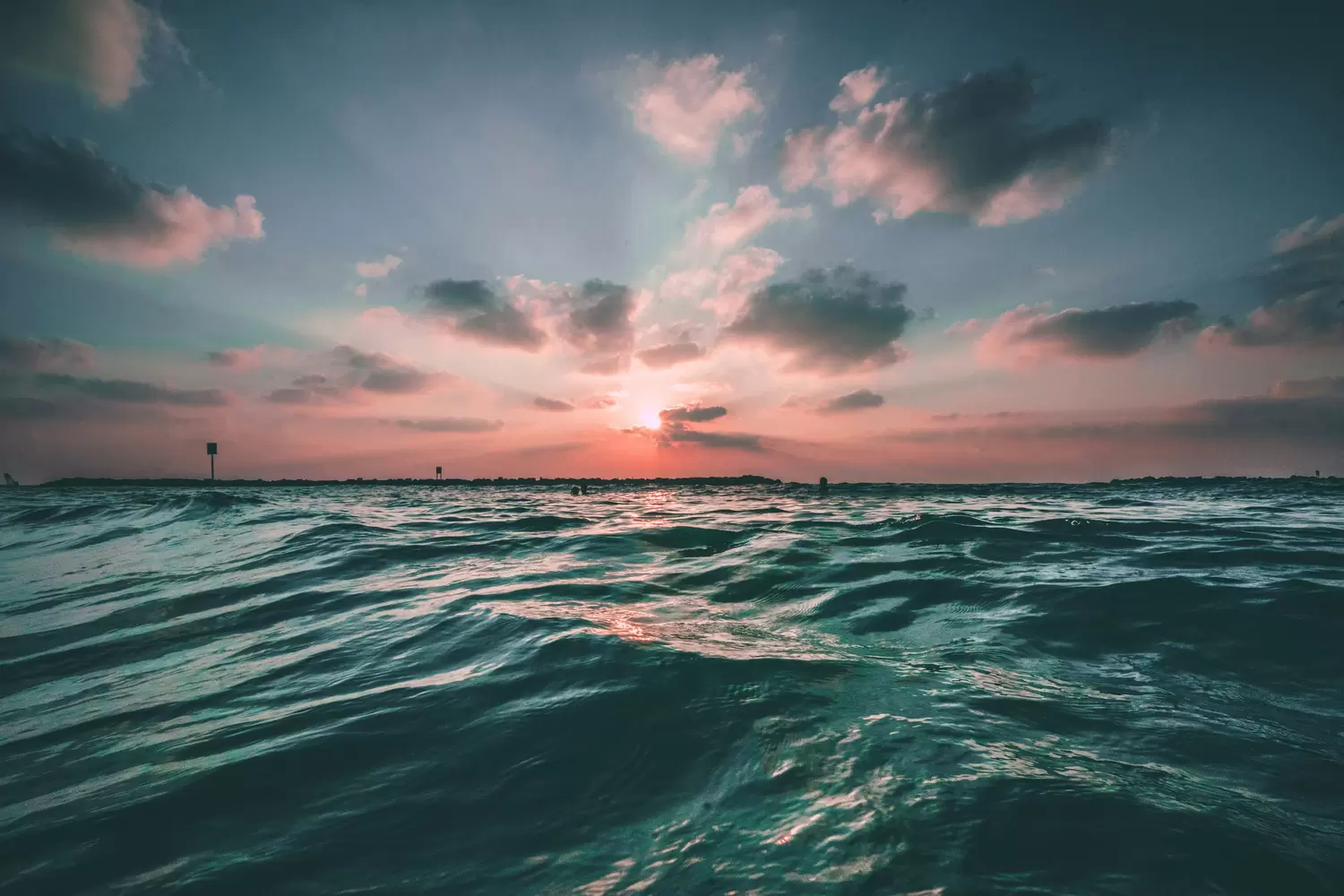 Ocean at sunset with a pink and teal sky